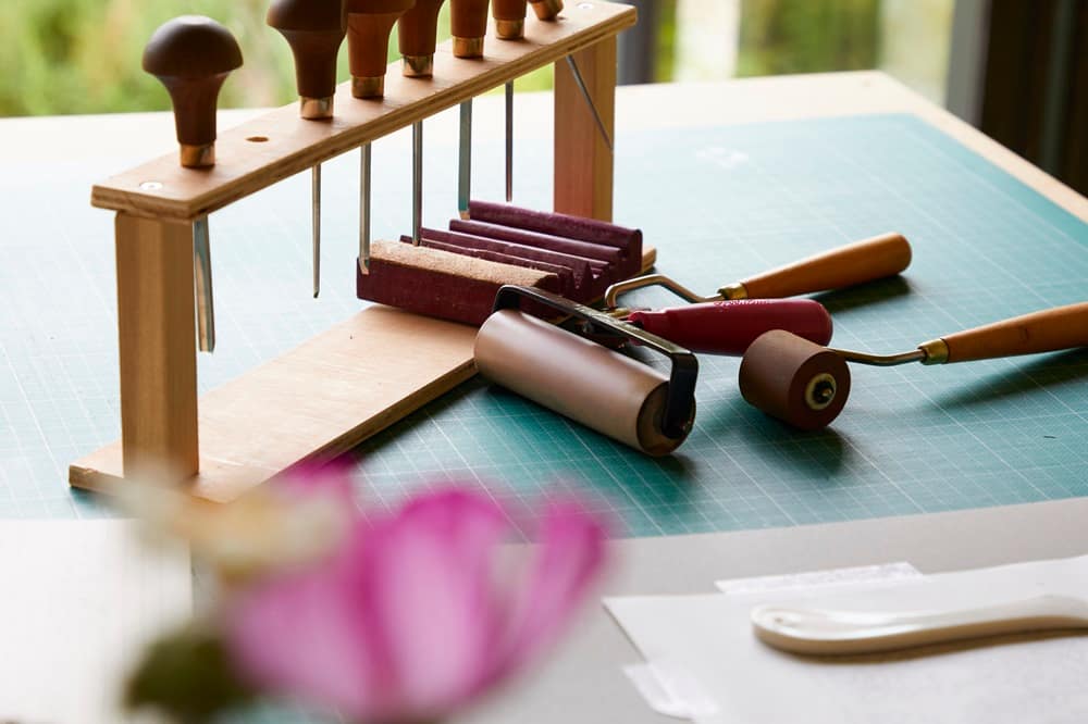 Lino cutting tools on a work bench with ink rollers