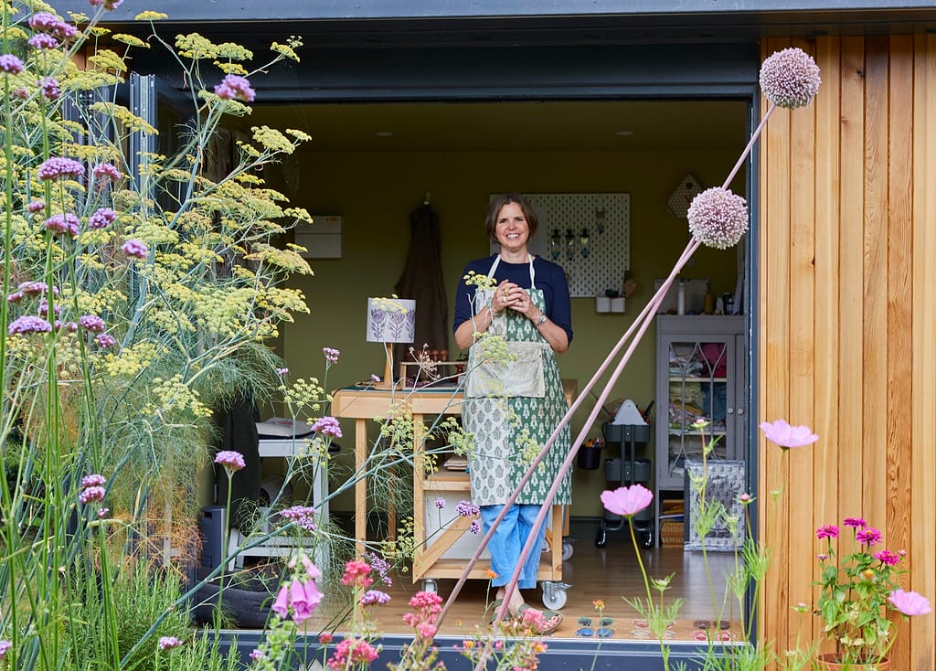 Julie Gardner standing in her printmaking studio in her garden